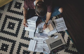 Man looking over his budget on the floor.