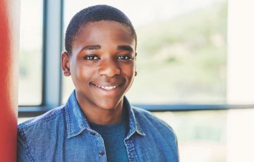 smiling kid leans against locker