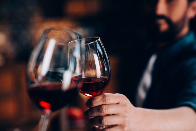 A man toasting with a glass of red wine.